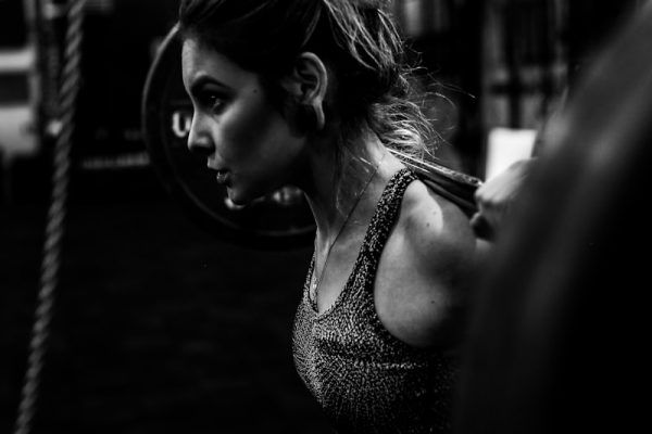 greyscale photo of woman in bralette inside room